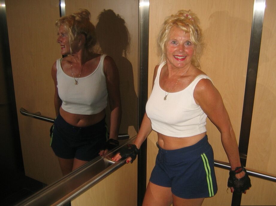 20P Mature blonde Ruth uncovers her breasts while working out at a gym