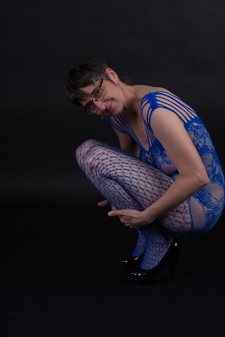 20P Un mannequin plus âgé pose dans un body sans entrejambe et des talons avec ses lunettes