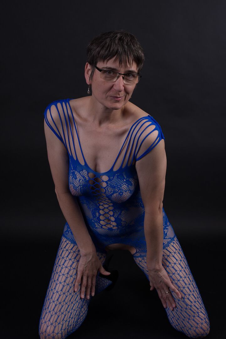 20P Un mannequin plus âgé pose dans un body sans entrejambe et des talons avec ses lunettes