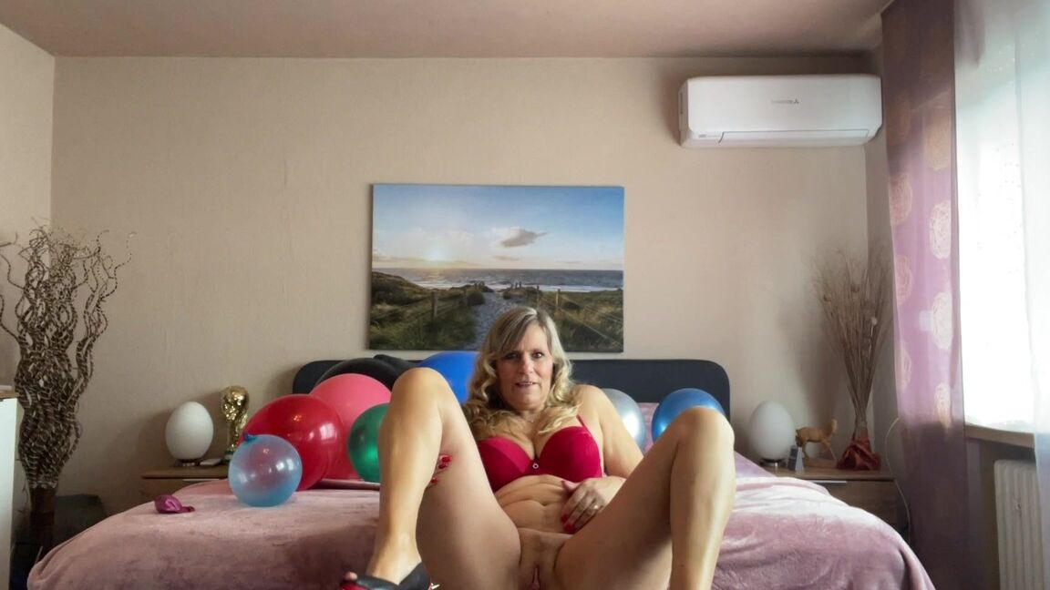 16P Middle-aged blonde Sweet Susi plays with balloons while getting naked on a bed