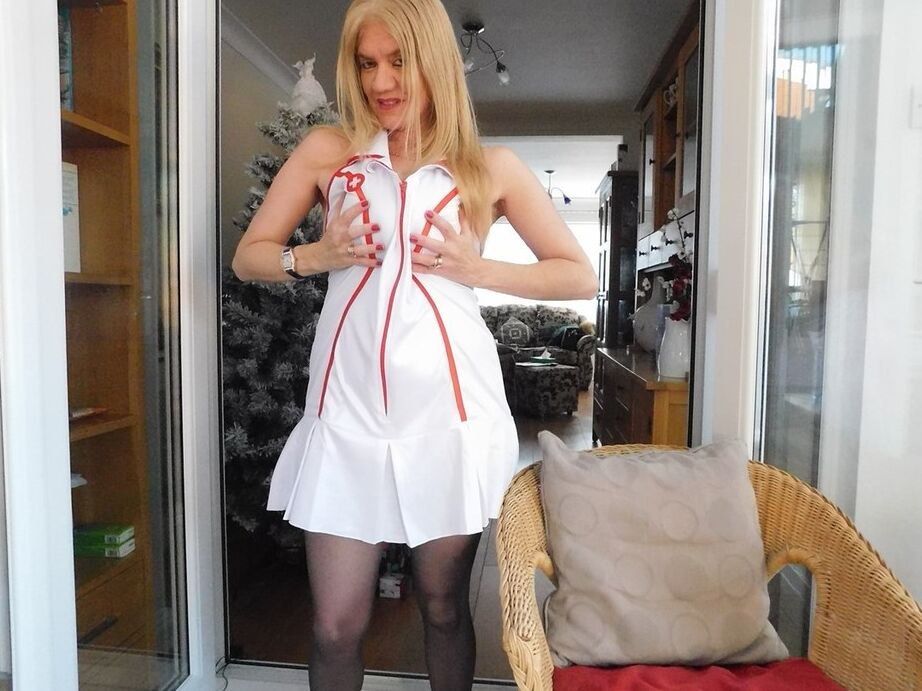 20P Older British nurse Lily May unzips her uniform on a wicker chair