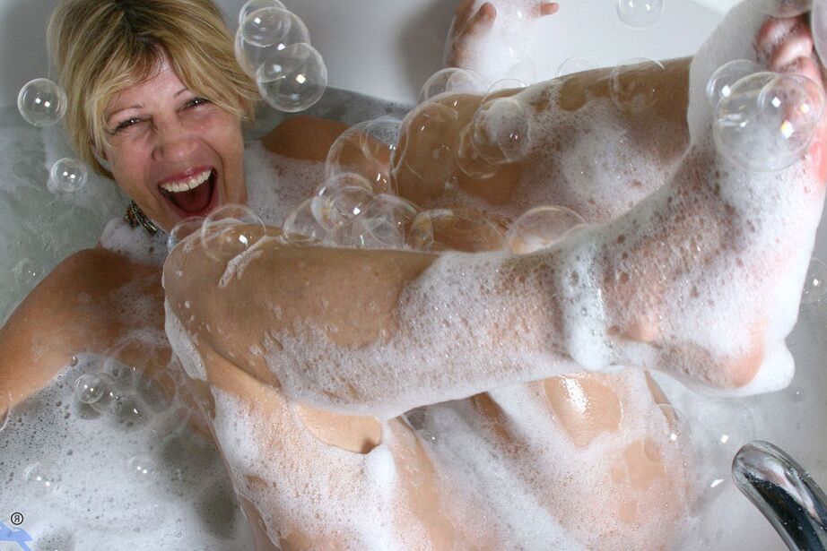 16P Une femme mûre fait couler de l'eau sur sa chatte tout en prenant un bain moussant