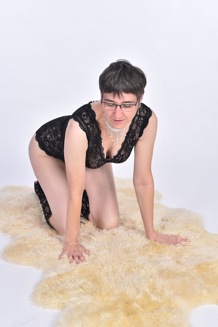 16P Mulher mais velha de cabelo curto expõe a bunda nua em um tapete de pele de urso
