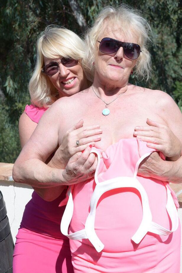 20P Melody, blonde mature, libère les seins d'une femme plus âgée d'une robe rose
