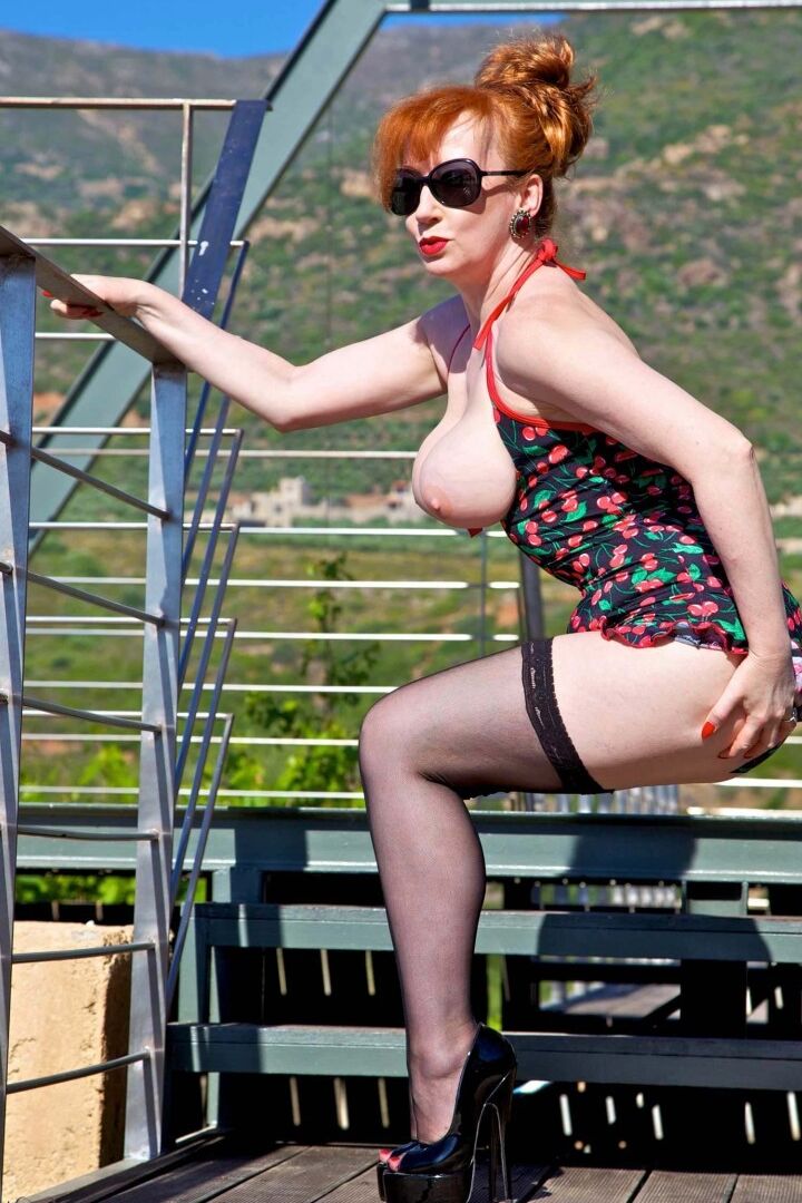 16P British model Red XXX exposes herself in shades and stockings on a walkway