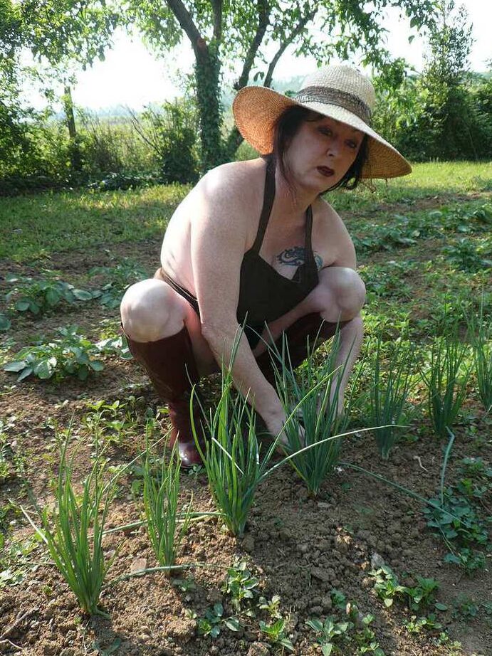 20P La señora madura Mary Bitch cuida su jardín desnuda con sombrero y delantal