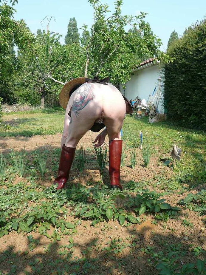 20P La señora madura Mary Bitch cuida su jardín desnuda con sombrero y delantal
