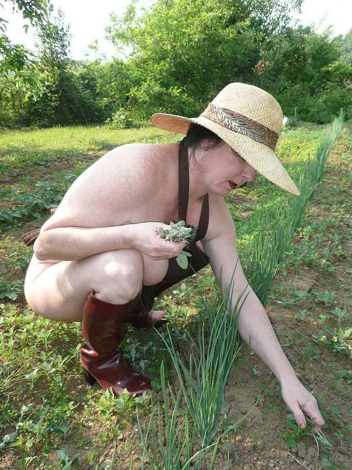 20P La señora madura Mary Bitch cuida su jardín desnuda con sombrero y delantal