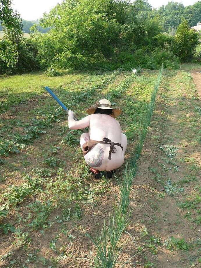 20P La señora madura Mary Bitch cuida su jardín desnuda con sombrero y delantal