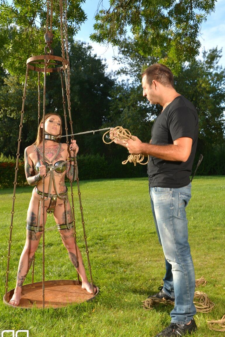 Lauren, soumise et encrée de 21P, pose dans une cage extérieure alors qu'elle est enchaînée.