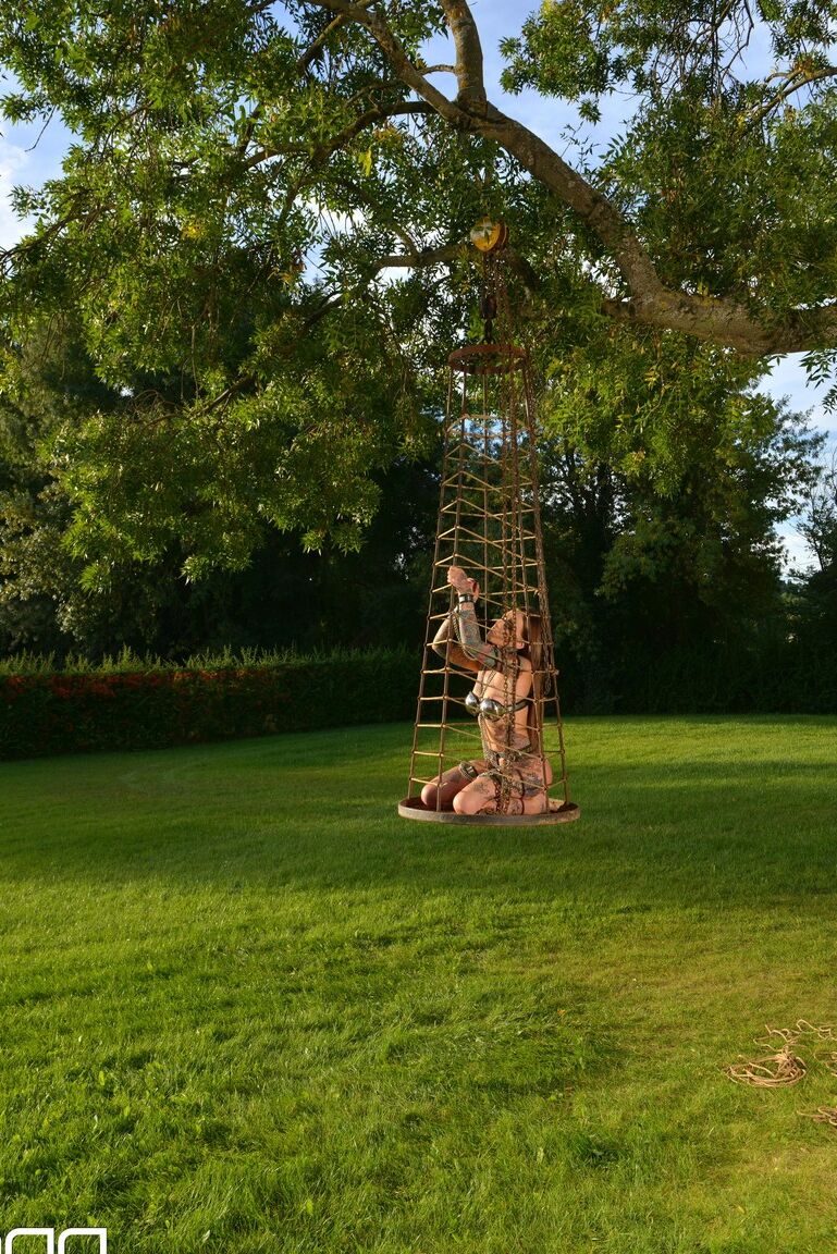 Lauren, soumise et encrée de 21P, pose dans une cage extérieure alors qu'elle est enchaînée.