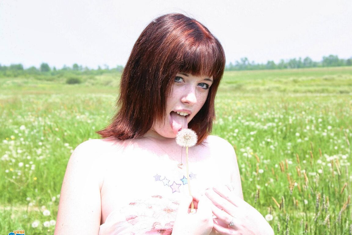 12P Young redhead Barbie A exposes her breasts against a building in a field