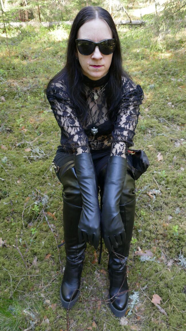 16P 服を着た女性は革の手袋とブーツを着用し、森の中で日よけをします