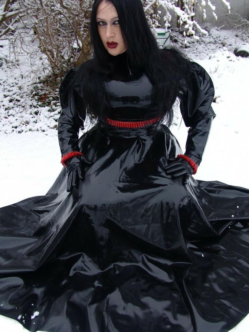 16P La mujer gótica Lady Angelina modela un vestido de látex negro sobre un suelo cubierto de nieve