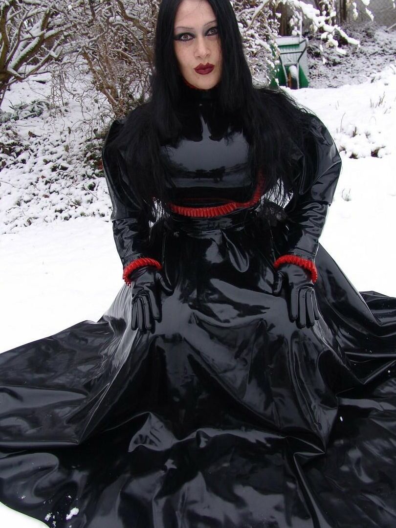 16P La mujer gótica Lady Angelina modela un vestido de látex negro sobre un suelo cubierto de nieve