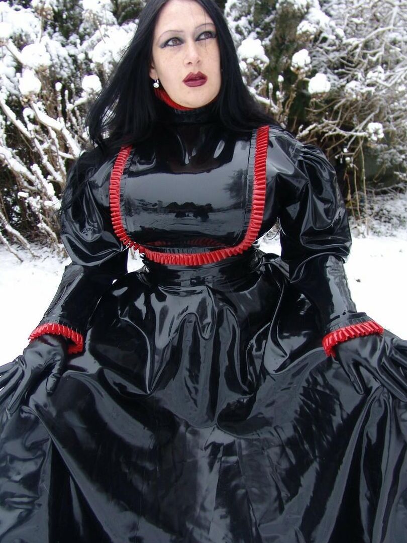 16P La mujer gótica Lady Angelina modela un vestido de látex negro sobre un suelo cubierto de nieve