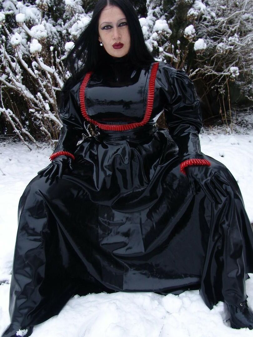 16P La mujer gótica Lady Angelina modela un vestido de látex negro sobre un suelo cubierto de nieve