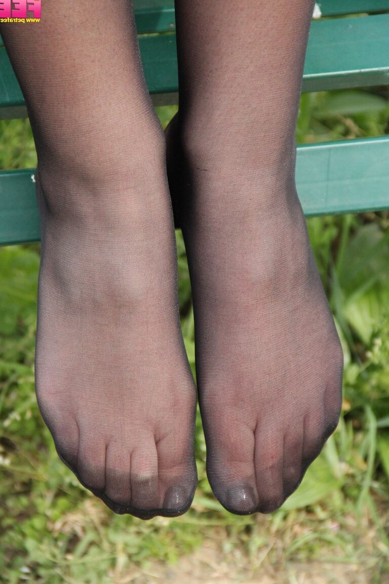 10P Solo model Petra rolls her nylons over legs and feet on bench in wooded area