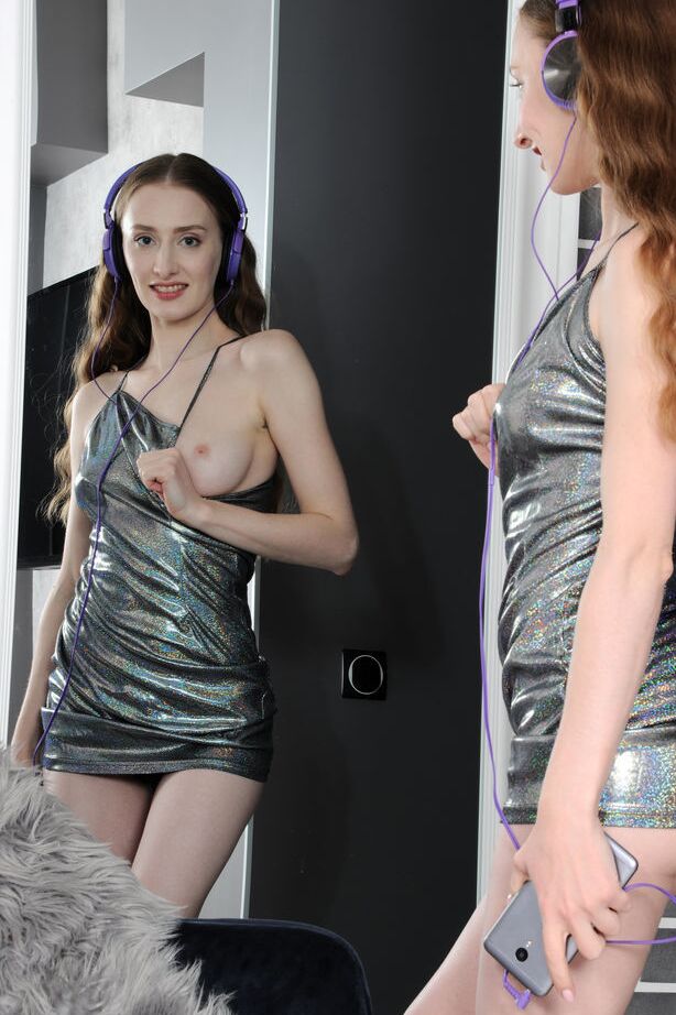 18P La joven delgada de pelo largo rojo Erin Pink se quita el vestido de cóctel y las bragas