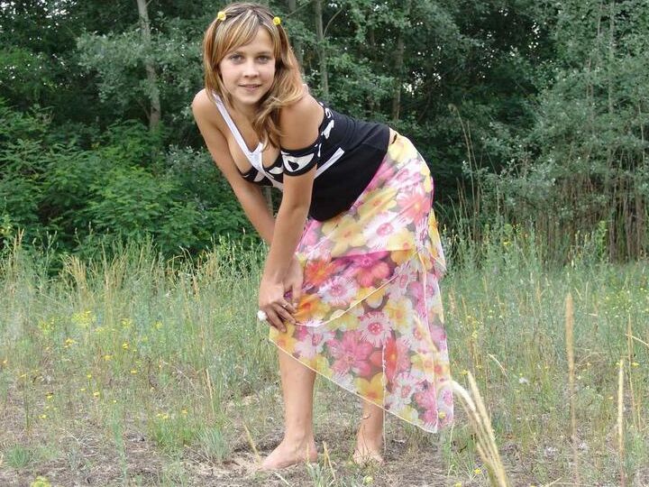 20P Barely legal cutie Liza strips naked in a clearing in front of a forest