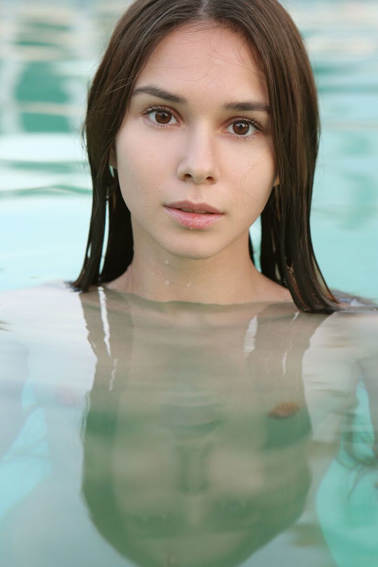 21P La adorable joven Leona Mia se desnuda y acaricia sus pequeñas tetas en la piscina