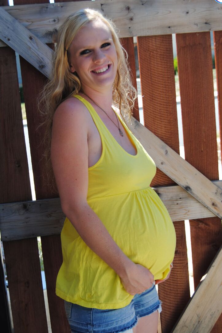 15P A amadora loira grávida Kristi mostra seus peitos e barriga inchados perto de um portão