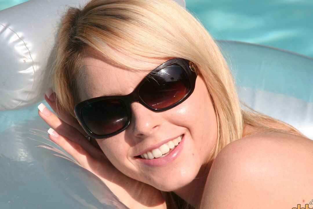 16P Kara amadora loira descansa em um colchão de ar apenas com óculos de sol