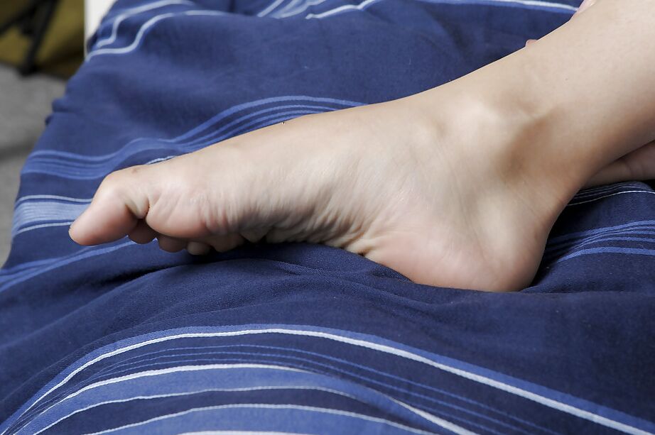 Kita Zen, une asiatique de 16P, pose pieds nus tout en faisant glisser sa culotte blanche le long de ses chevilles.