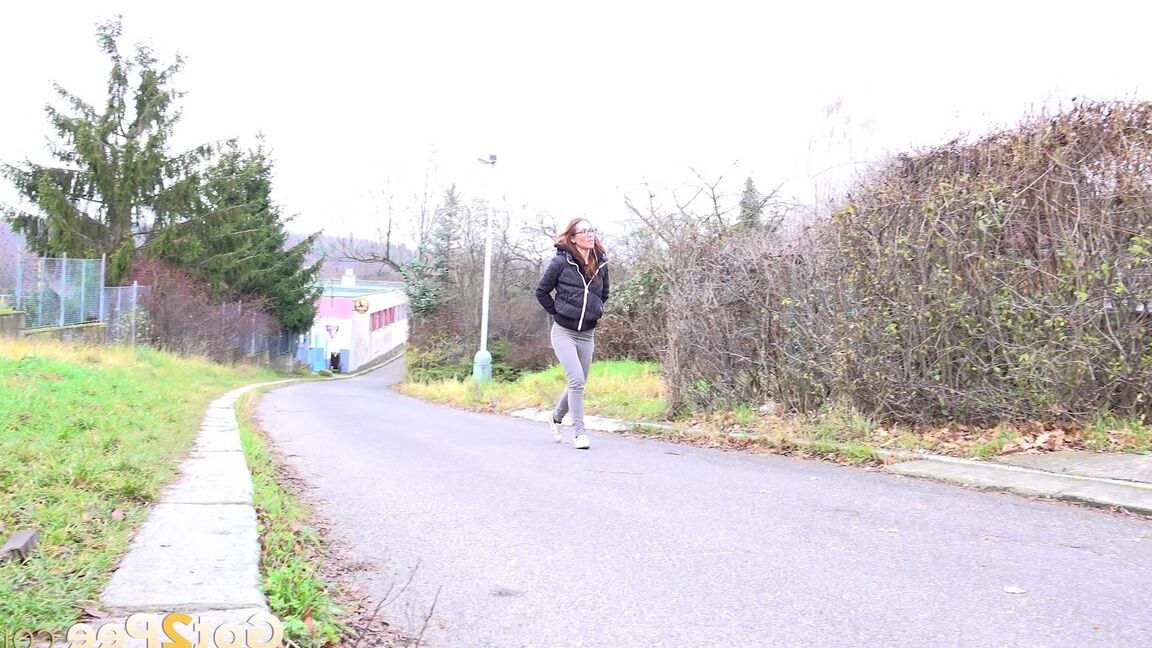 15P Redheaded girl pulls down her pants to take a piss in front of steel gates