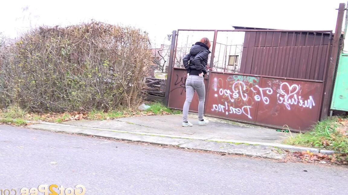 15P Redheaded girl pulls down her pants to take a piss in front of steel gates