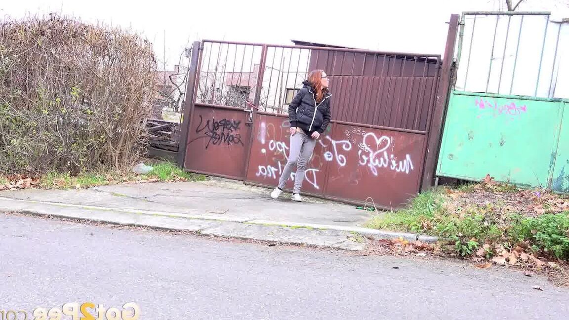 15P Redheaded girl pulls down her pants to take a piss in front of steel gates