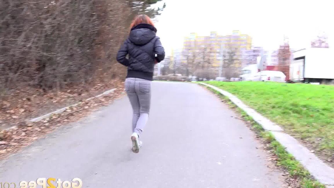 15P Redheaded girl pulls down her pants to take a piss in front of steel gates