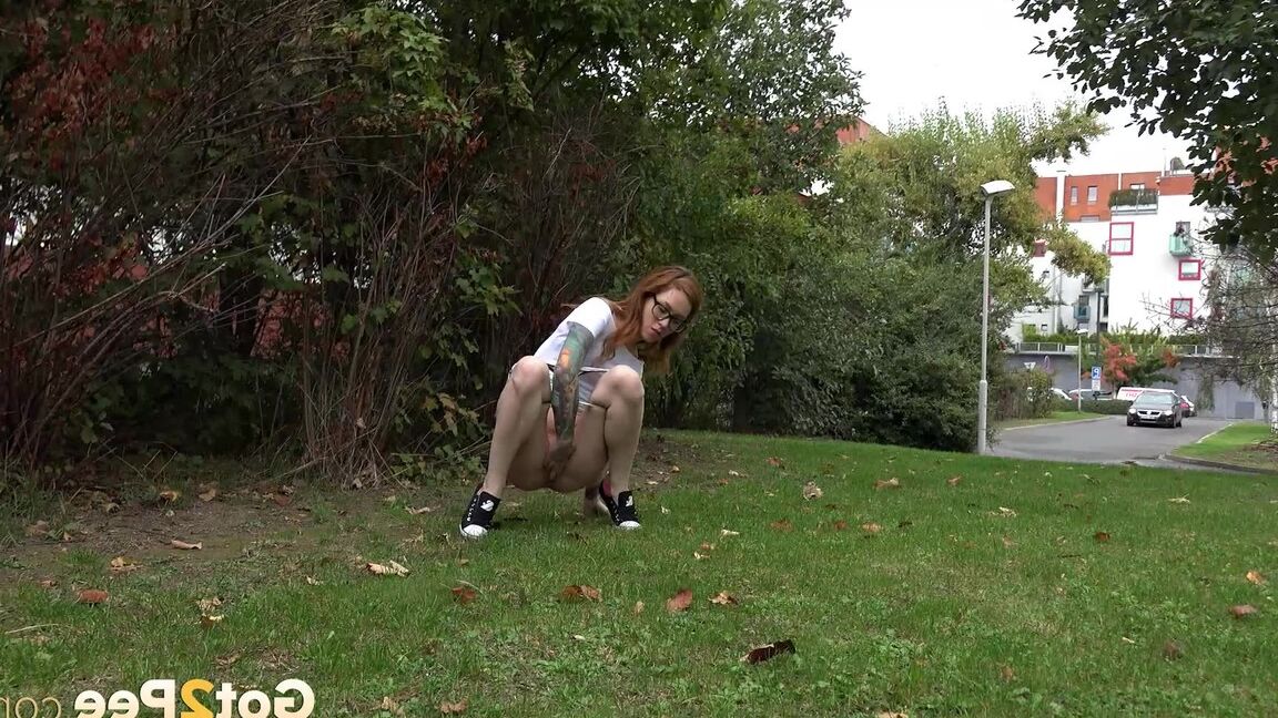 15P Une rousse à lunettes baisse sa culotte et fait pipi dans le parc
