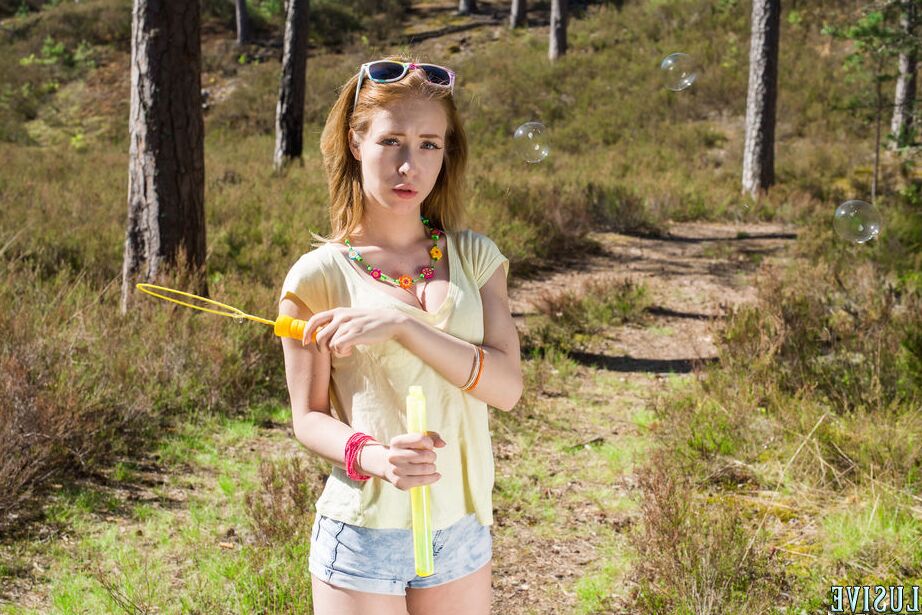 20P Young redhead Laska blows bubbles before posing naked in the woods