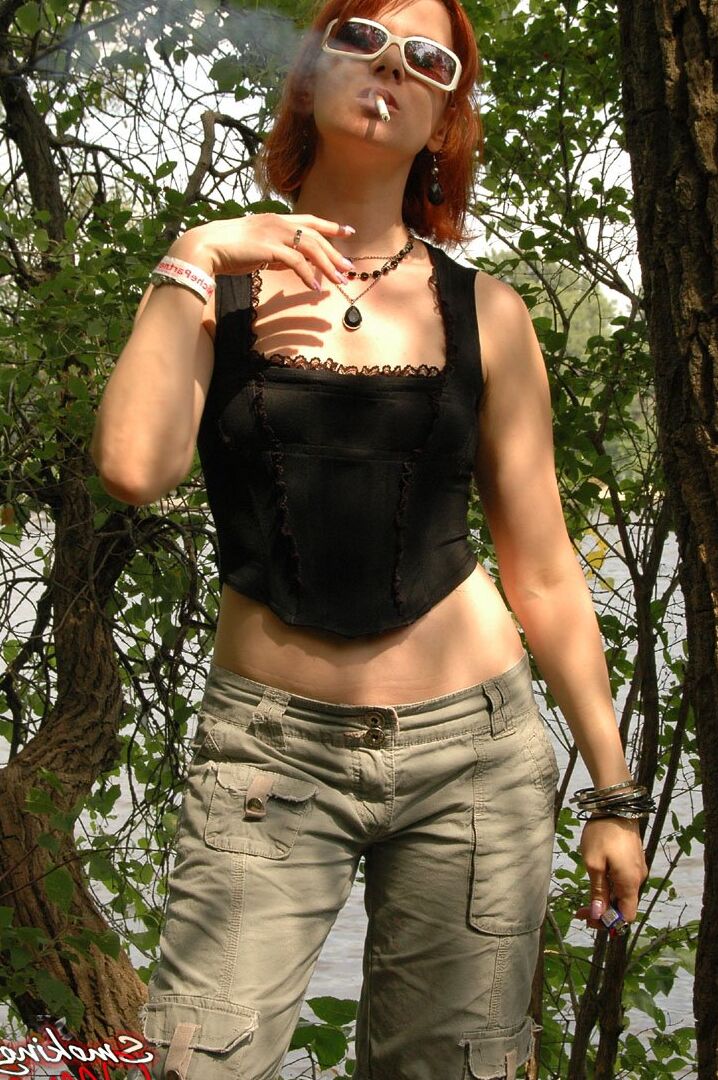15P Sexy redhead Mina wears long shorts and sunglasses while smoking in woods