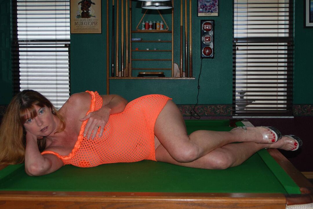 14P Dee Delmar, rousse et mature, porte des pâtés tout en montrant sa chatte sur une table de billard.