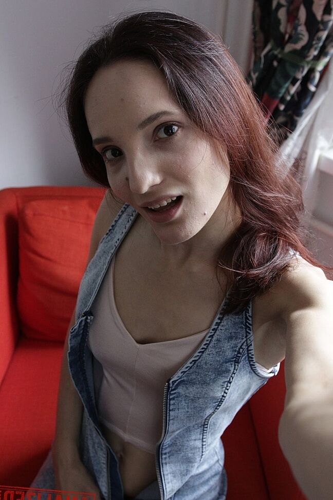 20P Slim amador Mia Sanders mostra seu decote e calcinha em um sofá vermelho