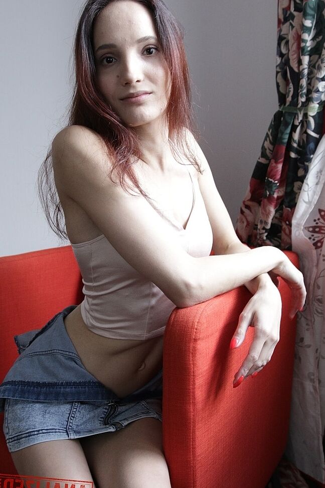 20P Slim amador Mia Sanders mostra seu decote e calcinha em um sofá vermelho