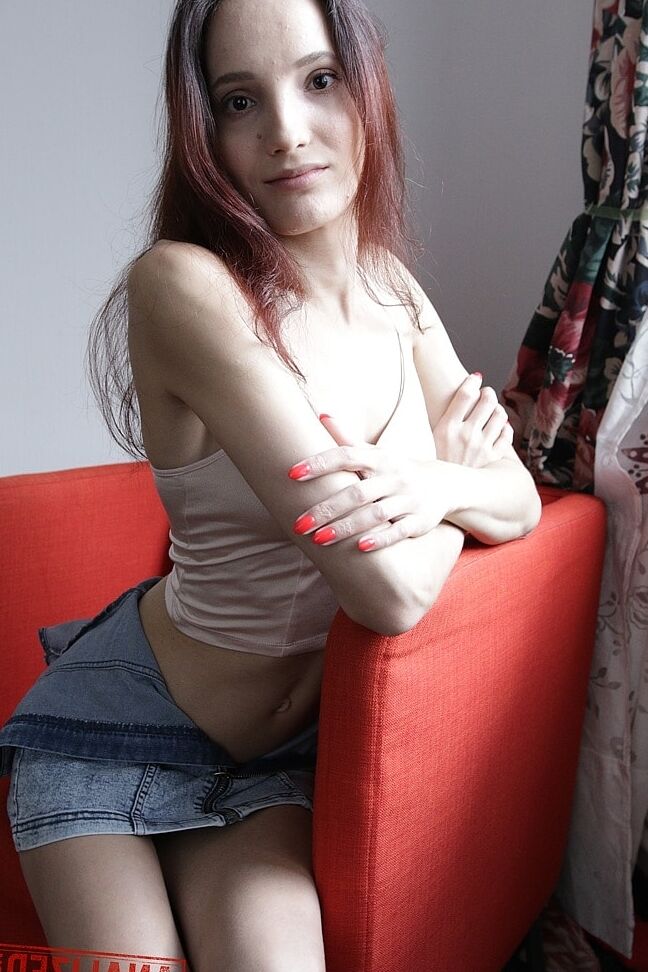 20P Slim amador Mia Sanders mostra seu decote e calcinha em um sofá vermelho