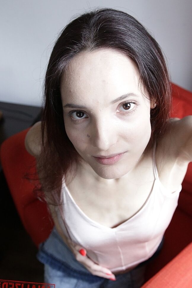 20P Slim amador Mia Sanders mostra seu decote e calcinha em um sofá vermelho