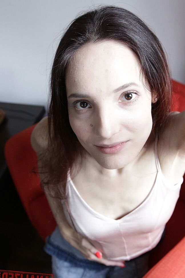 20P Slim amador Mia Sanders mostra seu decote e calcinha em um sofá vermelho