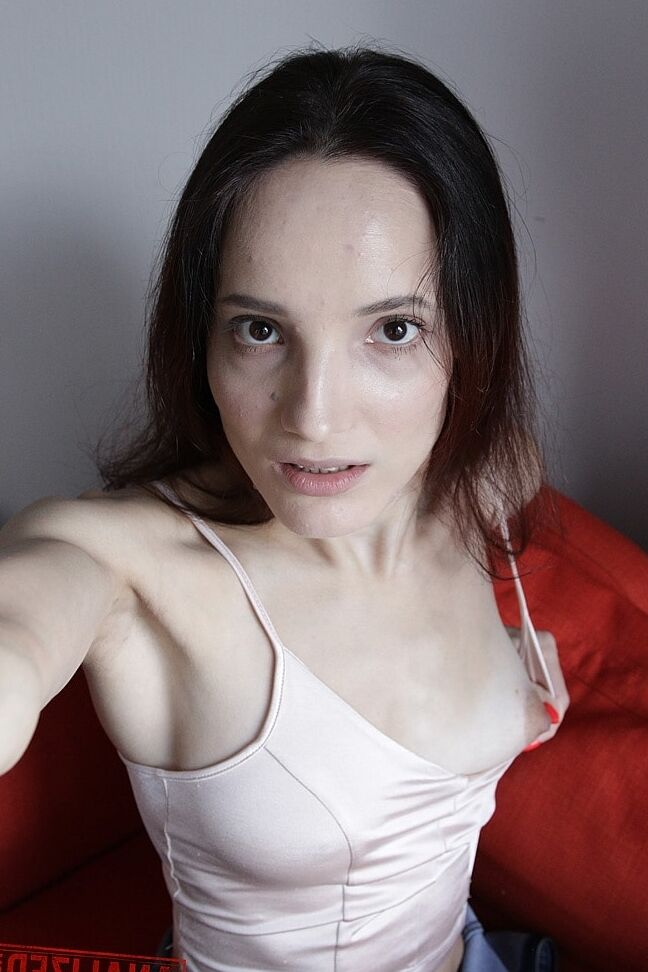 20P Slim amador Mia Sanders mostra seu decote e calcinha em um sofá vermelho
