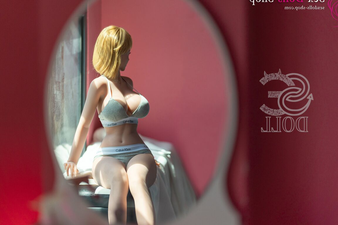 21P Linda boneca sexual pequena mostra seus seios grandes enquanto está deitada no tapete