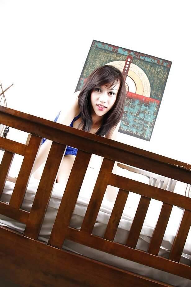16P Brünette junge asiatische Transe X posiert in einem blauen Kleid in ihrem Schlafzimmer