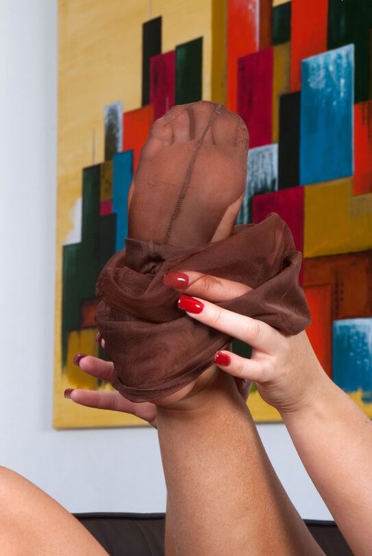Le modèle solo 16P Elle Brook fait rouler ses bas de nylon le long de ses jambes et sur ses pieds.