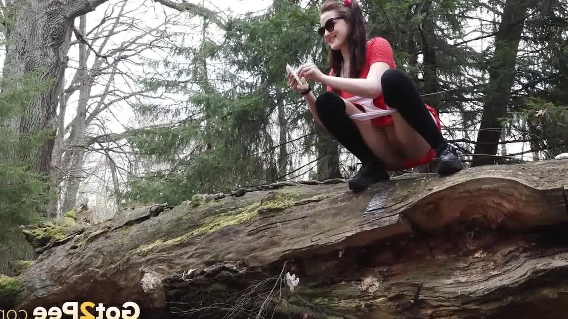 15P Sexy brunette takes a piss on a fallen tree while her girlfriend watches
