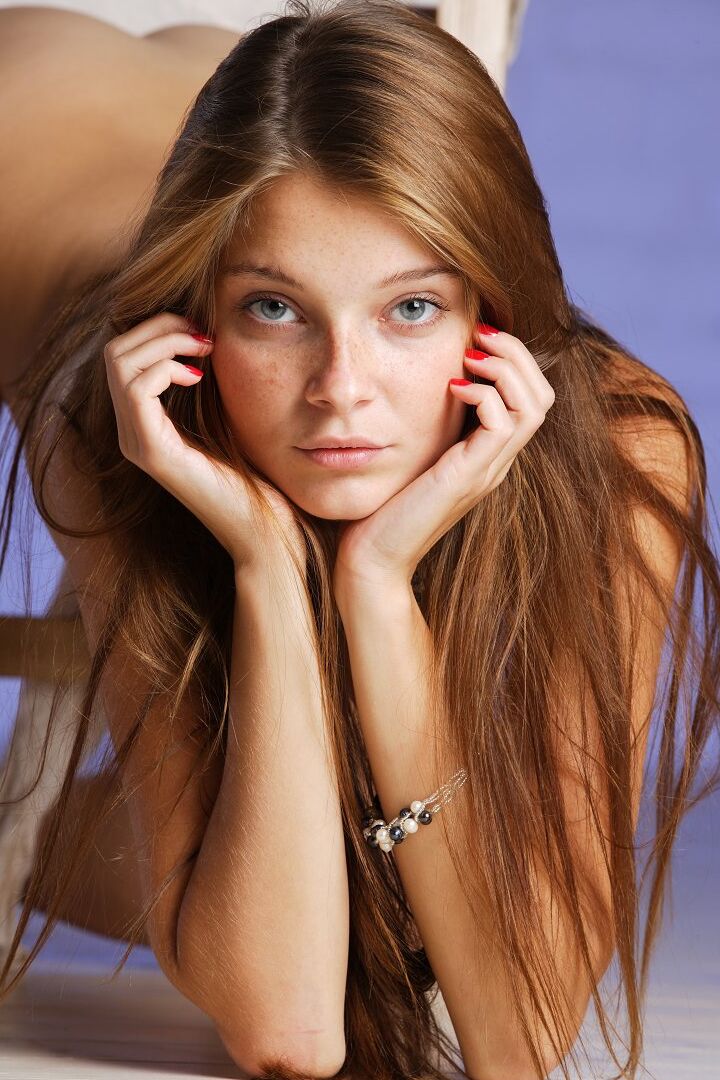 16P La jolie jeune mannequin Angelina B pose complètement nue sur une chaise en bois.