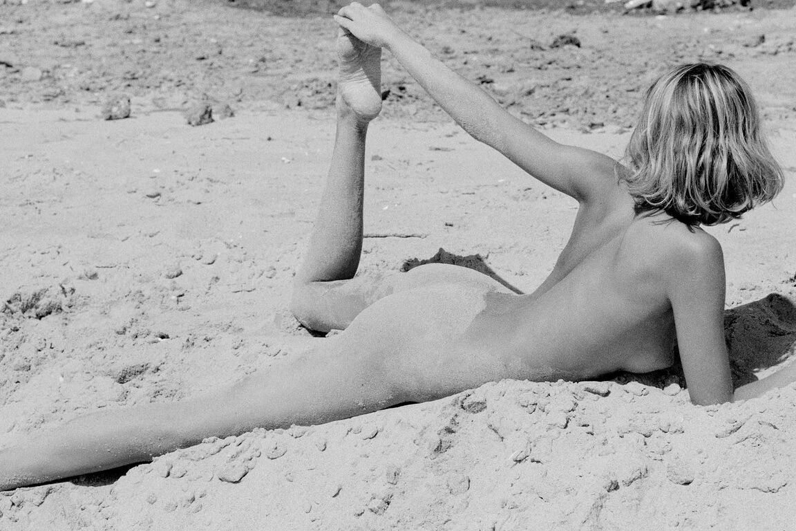 21P Barefoot babe with a skinny body Olga rubs her twat while rolling in the sand