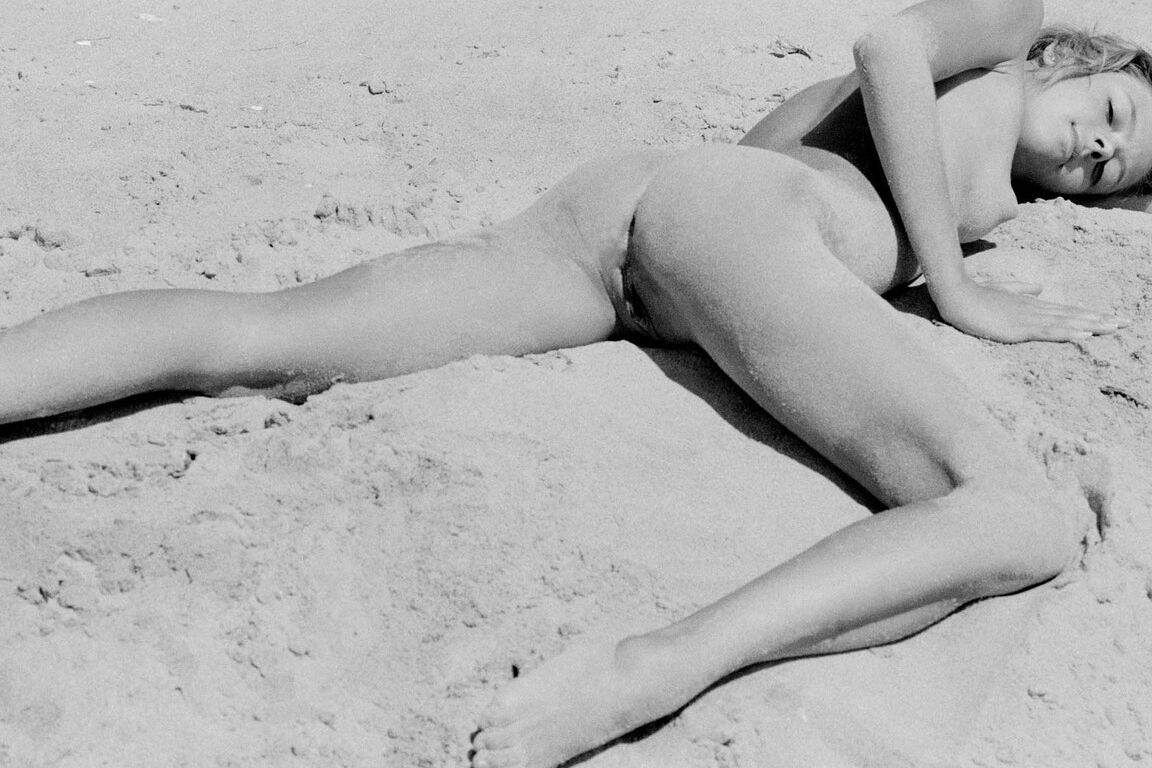 21P Barefoot babe with a skinny body Olga rubs her twat while rolling in the sand