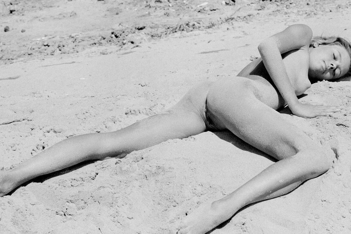 21P Barefoot babe with a skinny body Olga rubs her twat while rolling in the sand